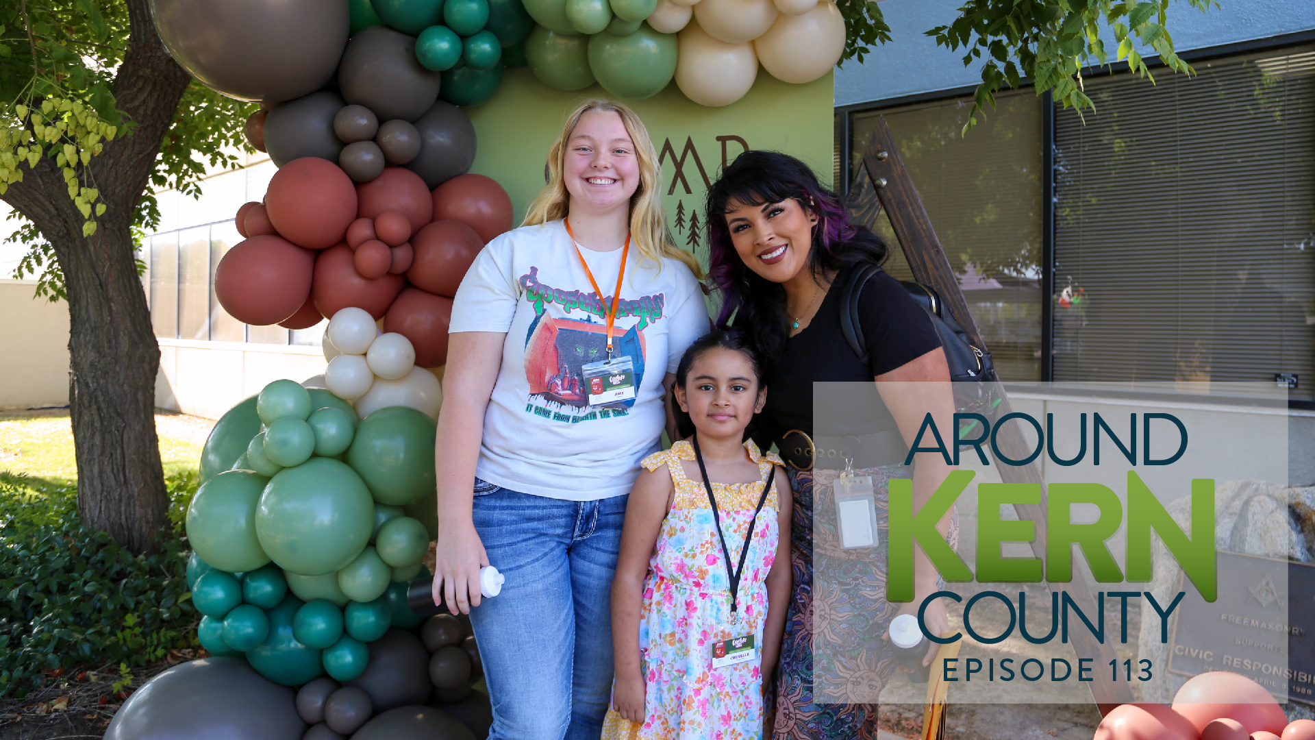 DHS employee with her kids at the Camp DHS event posing in front of a balloon wall