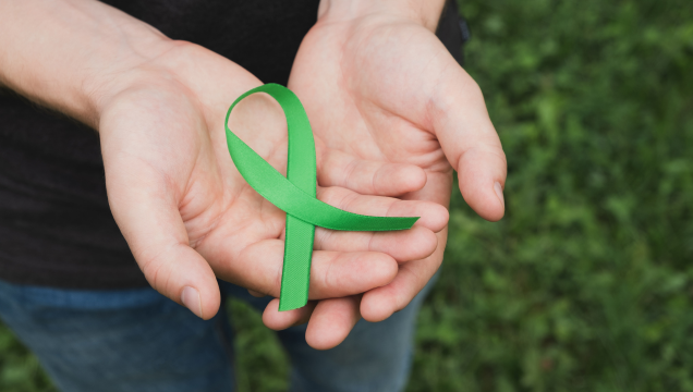 two hands holding a green ribbon for Mental Health Awareness Month