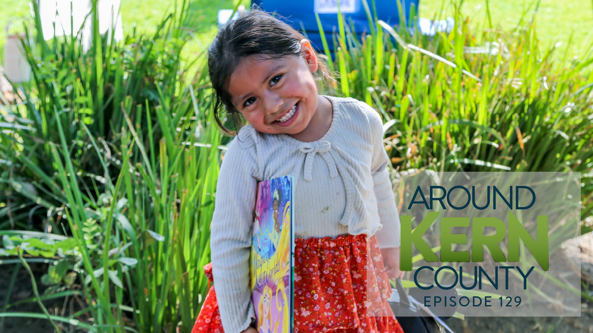 little girls with a book in hand posing for the camera smiling